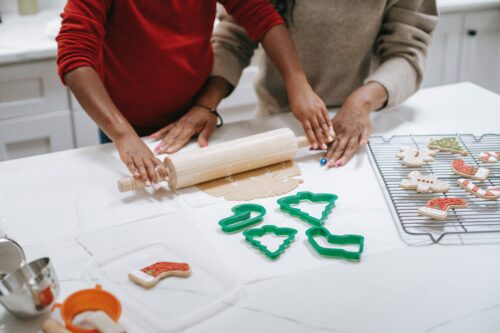 A family makes sourdough cookie decoration with Christmas-themed cookie cutters.